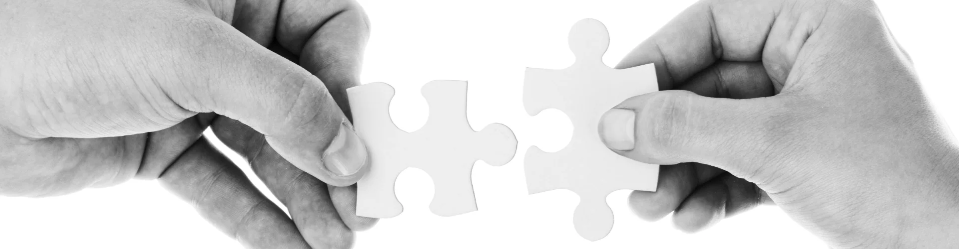 Deux mains essayant d'assembler deux pièces de puzzle ensemble